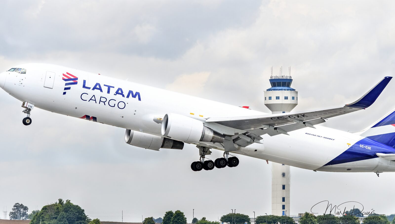 Cargo aircraft climbing out after takeoff with airport control tower in background