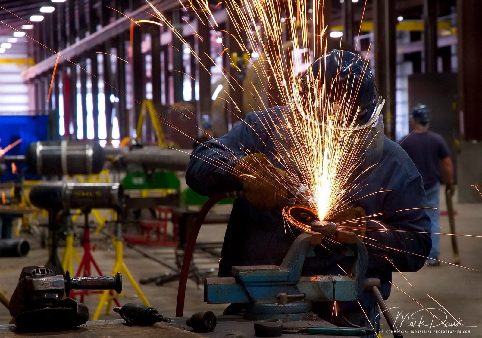 Welder grinding metal with sparks flying at a manufacturing plant